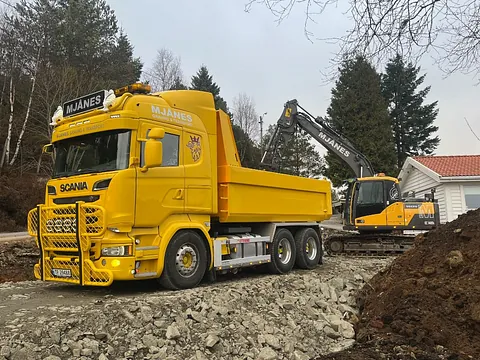 Gravemaskin heller masse inn i gul lastebil