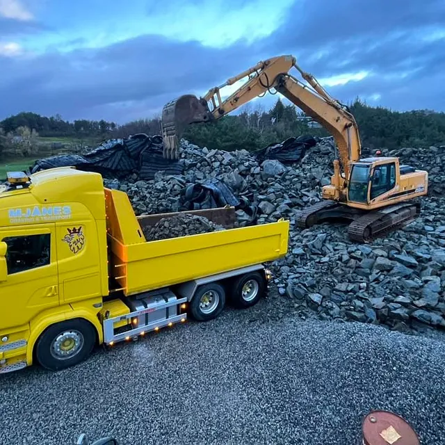 Gravemaskin laster stein inn i transportbil
