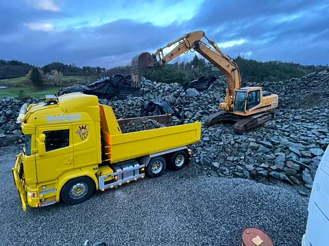 Gravemaskin laster stein inn i transportbil